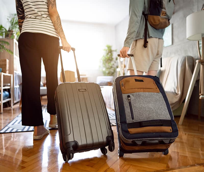 A couple rolling their suitcases into their Airbnb.