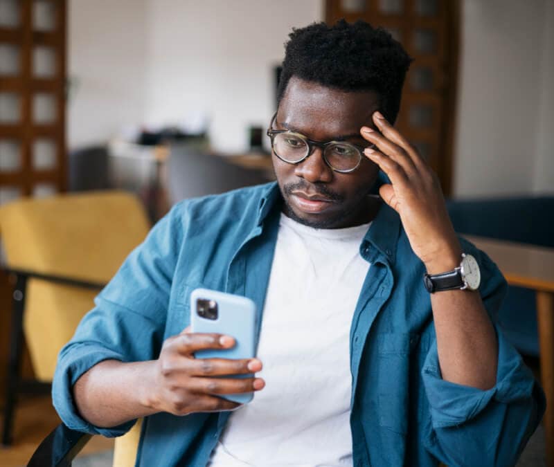 A man looking at his phone wondering, “Can iPhones get hacked?”