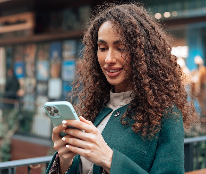 A curly-haired woman checking her iPhone for viruses.