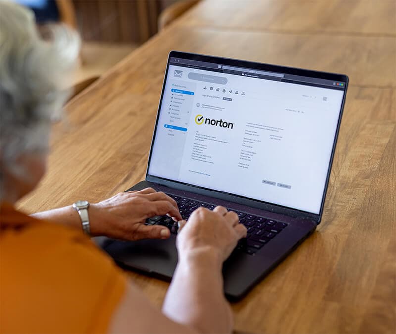 A woman checking emails on her laptop, wondering whether she’s received a scam email supposedly from Norton.