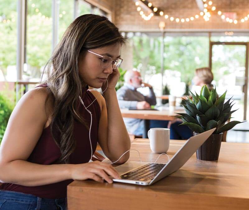 A woman connects to public Wi-Fi to work at a coffee shop.