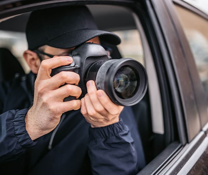 A man with a camera in a car spying on his neighbours.