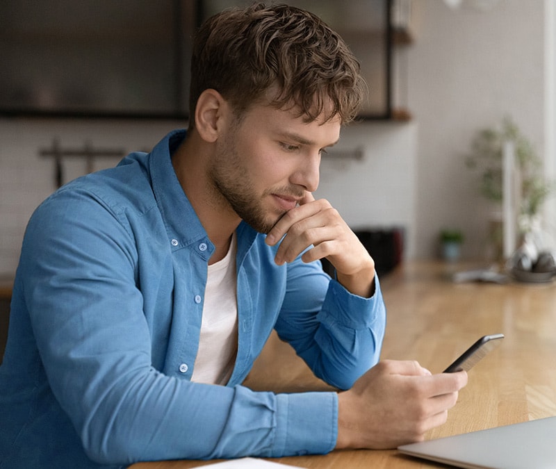 Person with a confused expression looking at their phone, potentially wondering “How to tell if someone blocked your number?”