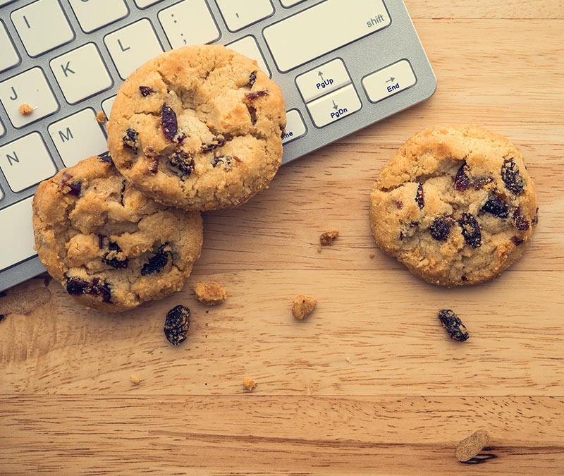 Chocolate cookies on a wooden table and keyboard, illustrating the similarity to computer cookies.