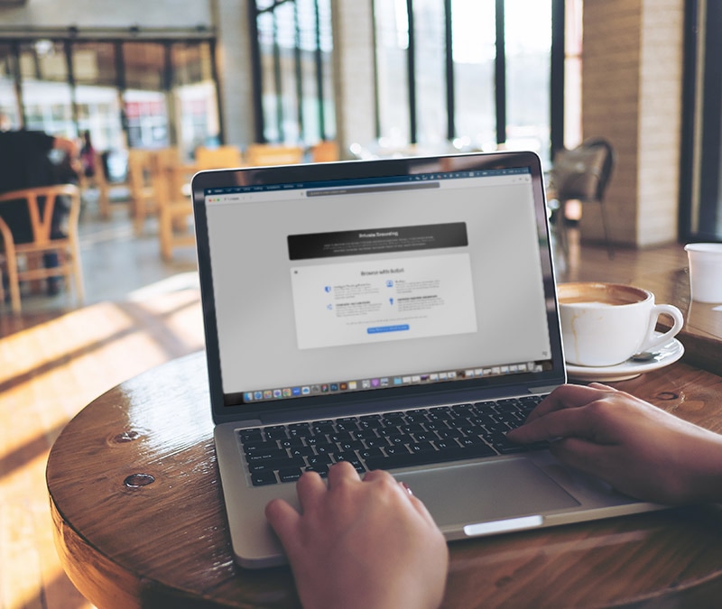 A person surfing privately on a Macbook Pro in a coffee shop.
