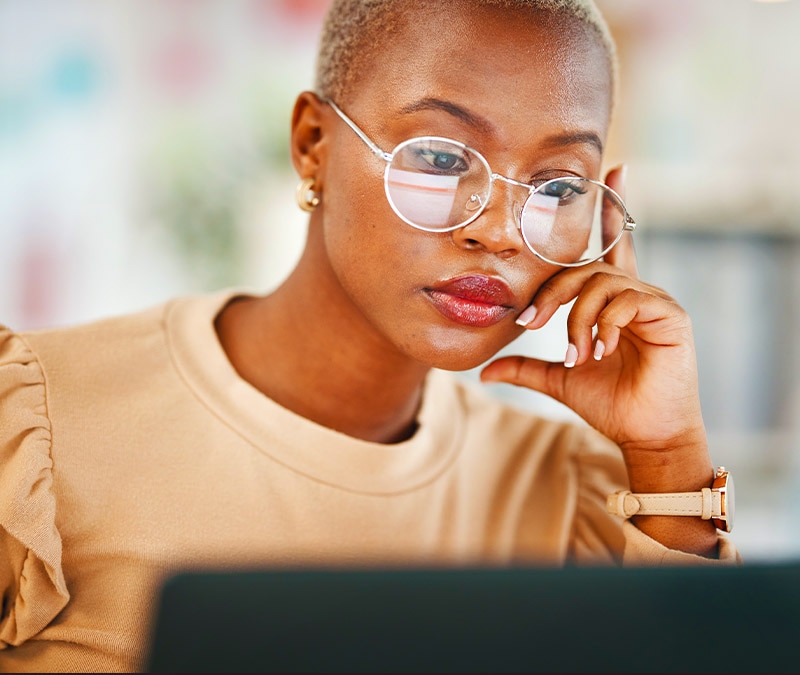 A woman is looking at her laptop, thinking about what to do with a scammer who has her email.