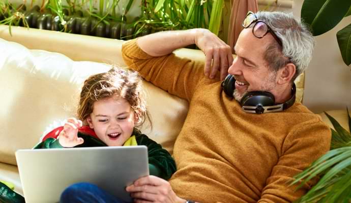 Man wearing headphones, showing little girl something on a laptop