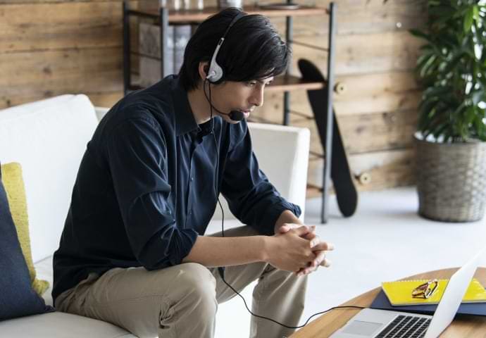 Man wearing headphones connected to laptop
